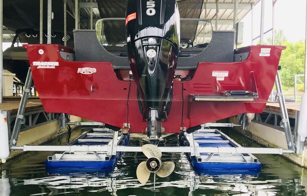 Red single motor boat on a 4500# boat lift in the up position