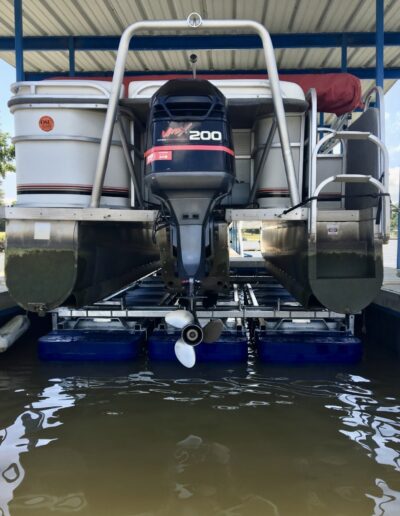 Tritoon boat on a 6000# Shallow Water boat lift in the up position in an outdoor boat slip
